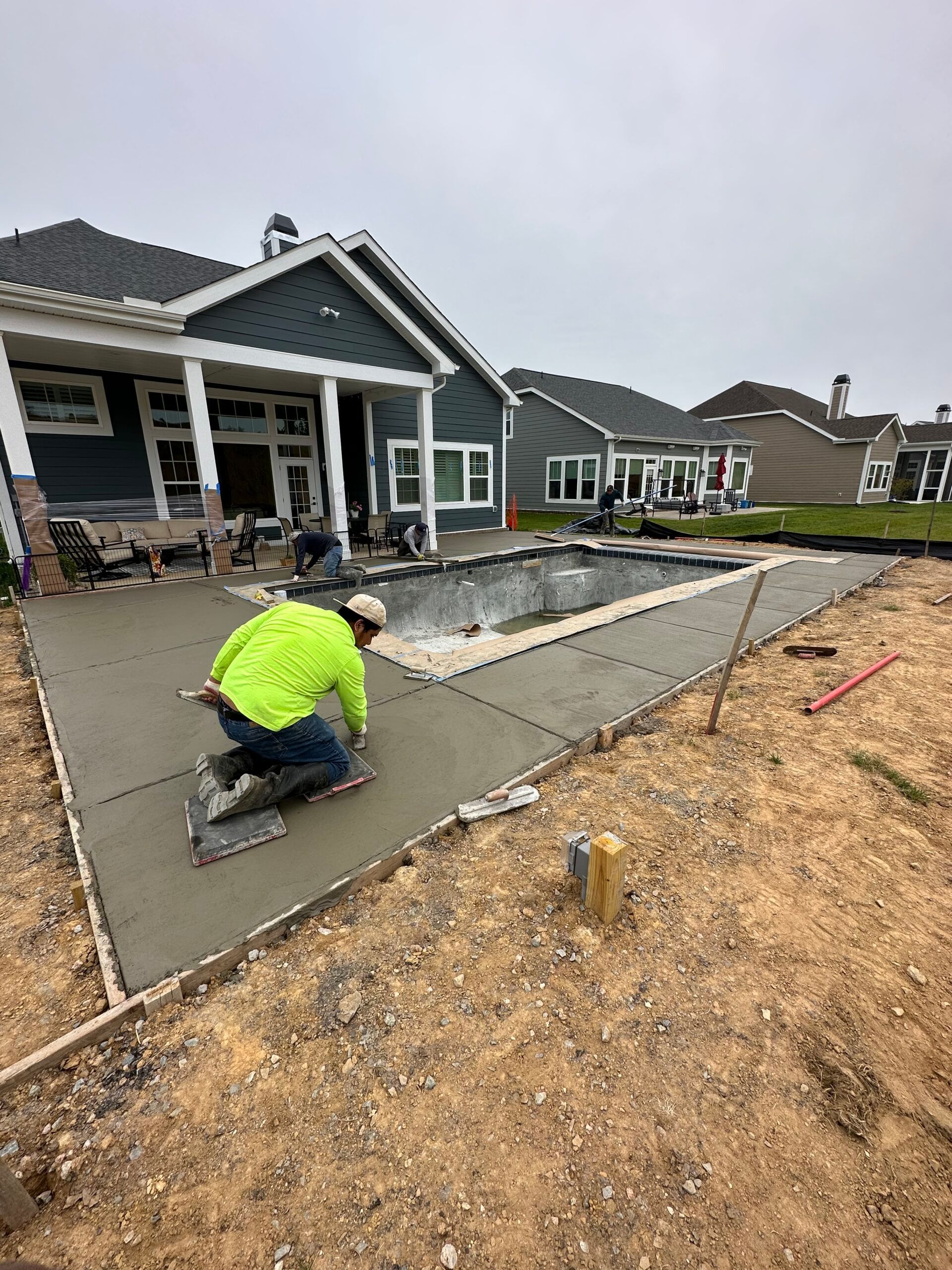 A man is working on a concrete patio in front of a house.