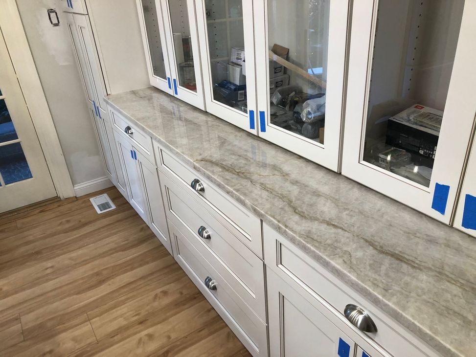 A kitchen with white cabinets , granite counter tops , stainless steel appliances and a large island.