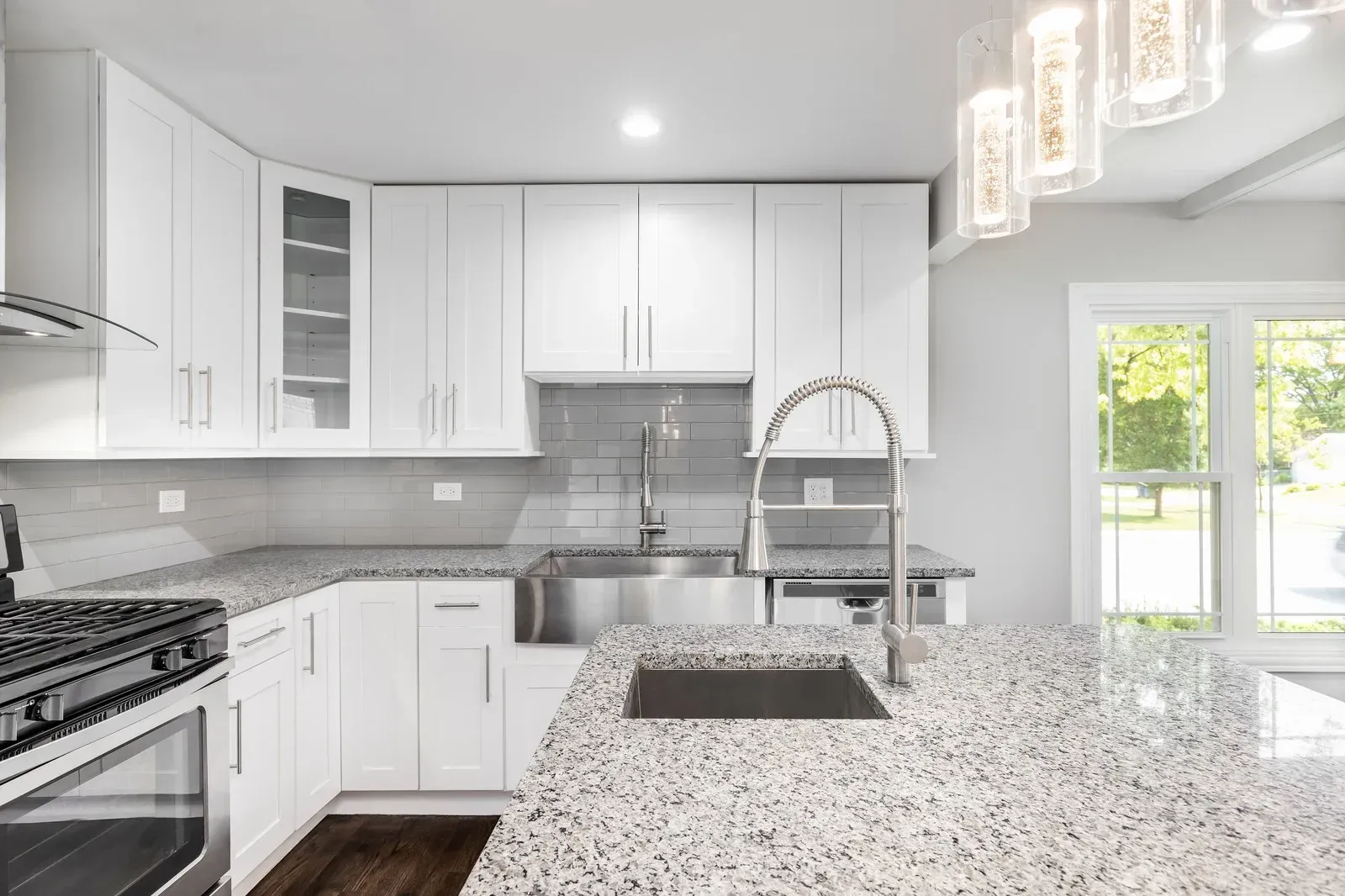 A kitchen with white cabinets , granite counter tops , stainless steel appliances and a sink.