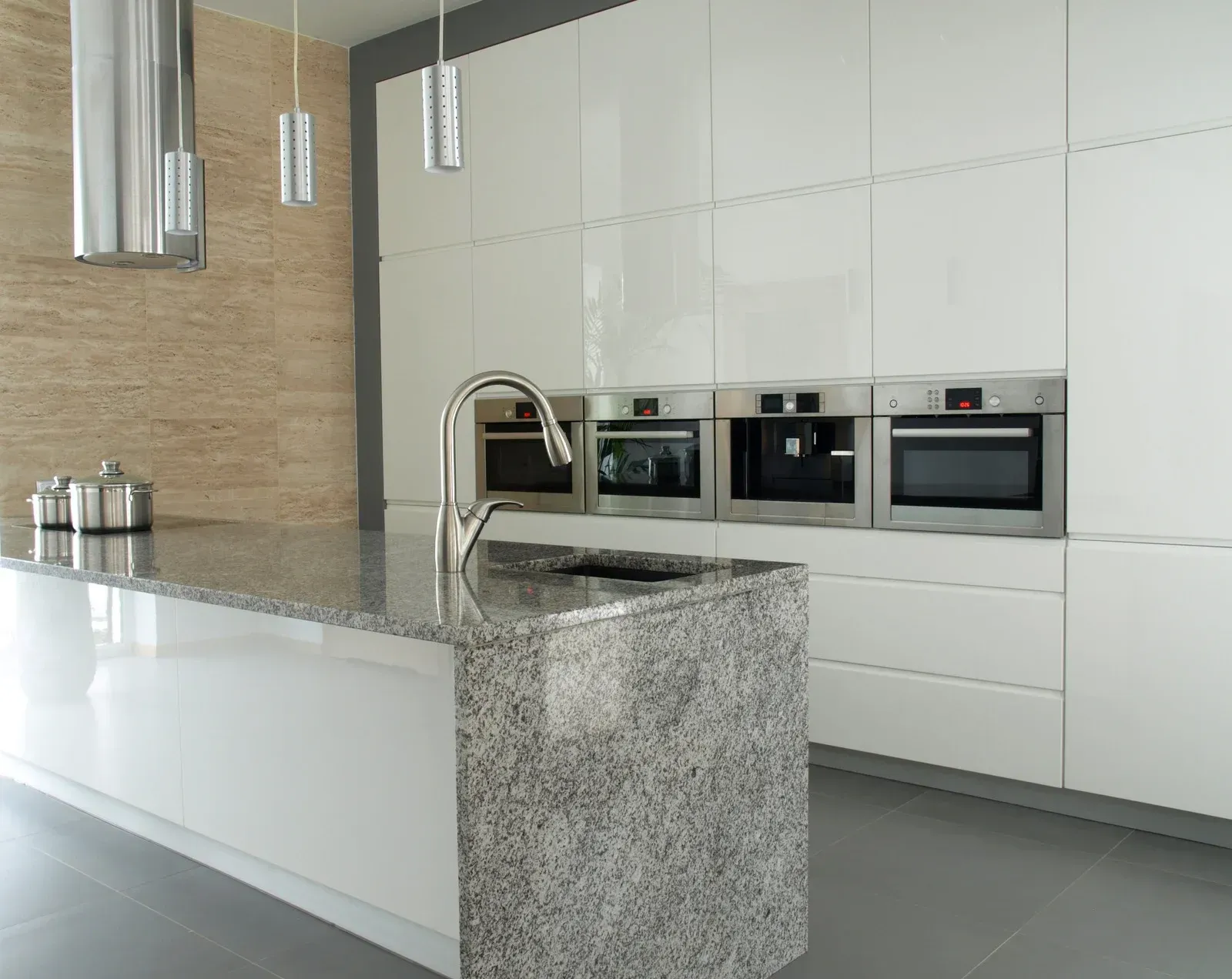 A kitchen with white cabinets , granite counter tops , stainless steel appliances and a large island.