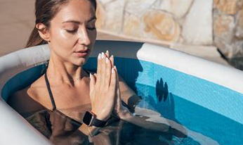 A woman is sitting in a bathtub with her hands folded in prayer.