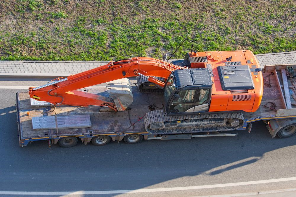 An Aerial View of a Construction Vehicle on a Trailer on a Highway — Dino's Bobcat–Bitumen & Excavator Hire in Monto, QLD