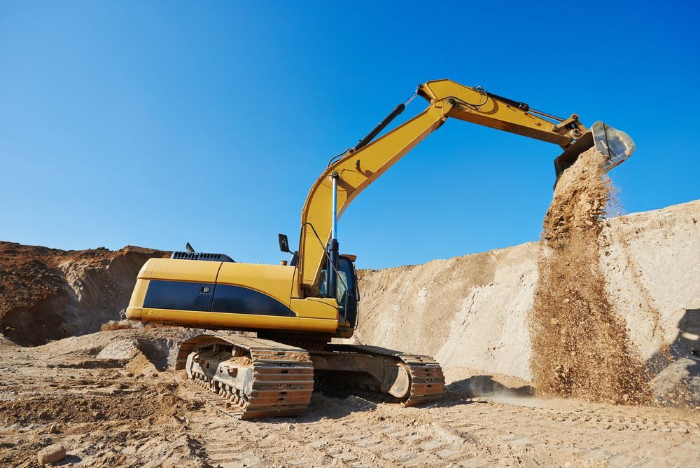 A Yellow Excavator is Loading Sand Into a Pile — Dino's Bobcat–Bitumen & Excavator Hire in Cushnie, QLD