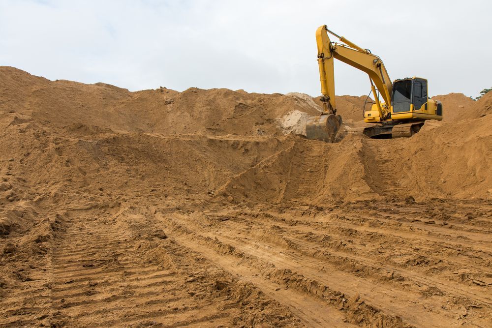 A Yellow Excavator is Digging in a Pile of Dirt — Dino's Bobcat–Bitumen & Excavator Hire in North Burnett, QLD