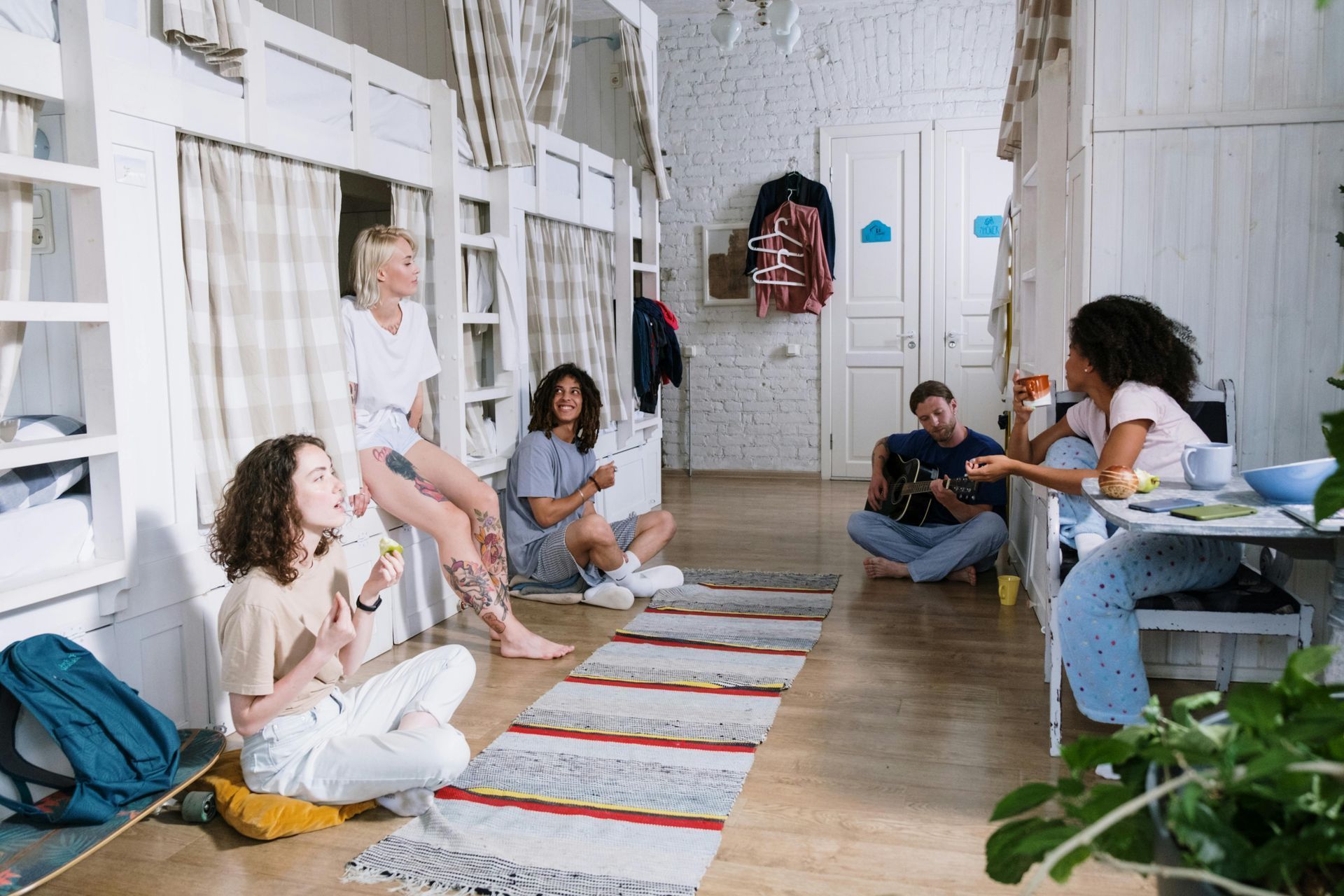 People sitting in a bright hallway, chatting and relaxing on chairs and rugs.