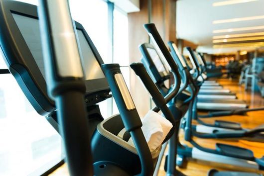 Row of treadmills in a bright gym with a white towel draped over one machine
