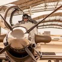 A man is sitting in the cockpit of a small propeller plane.