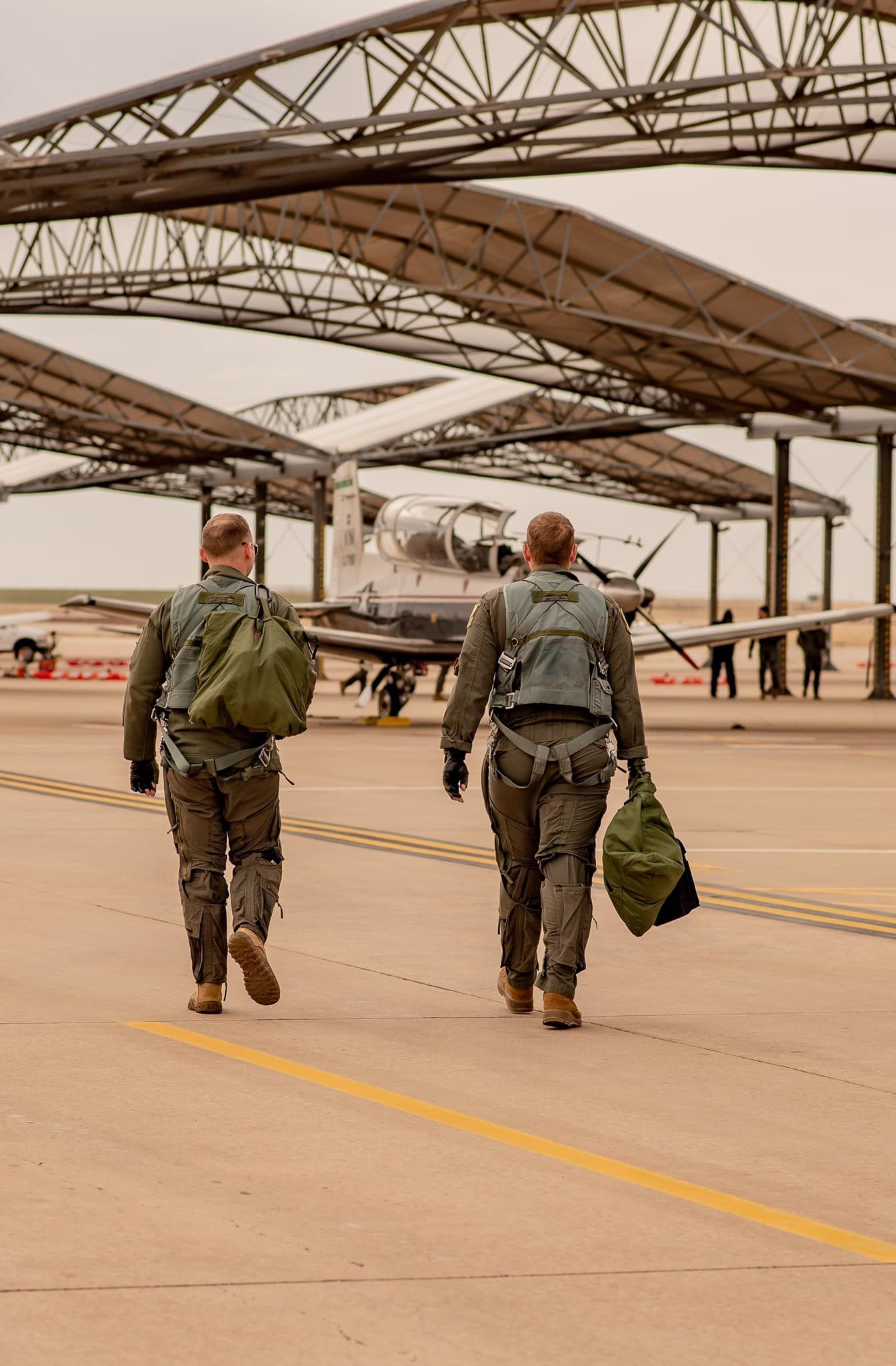 Two soldiers are walking towards a plane on a runway.