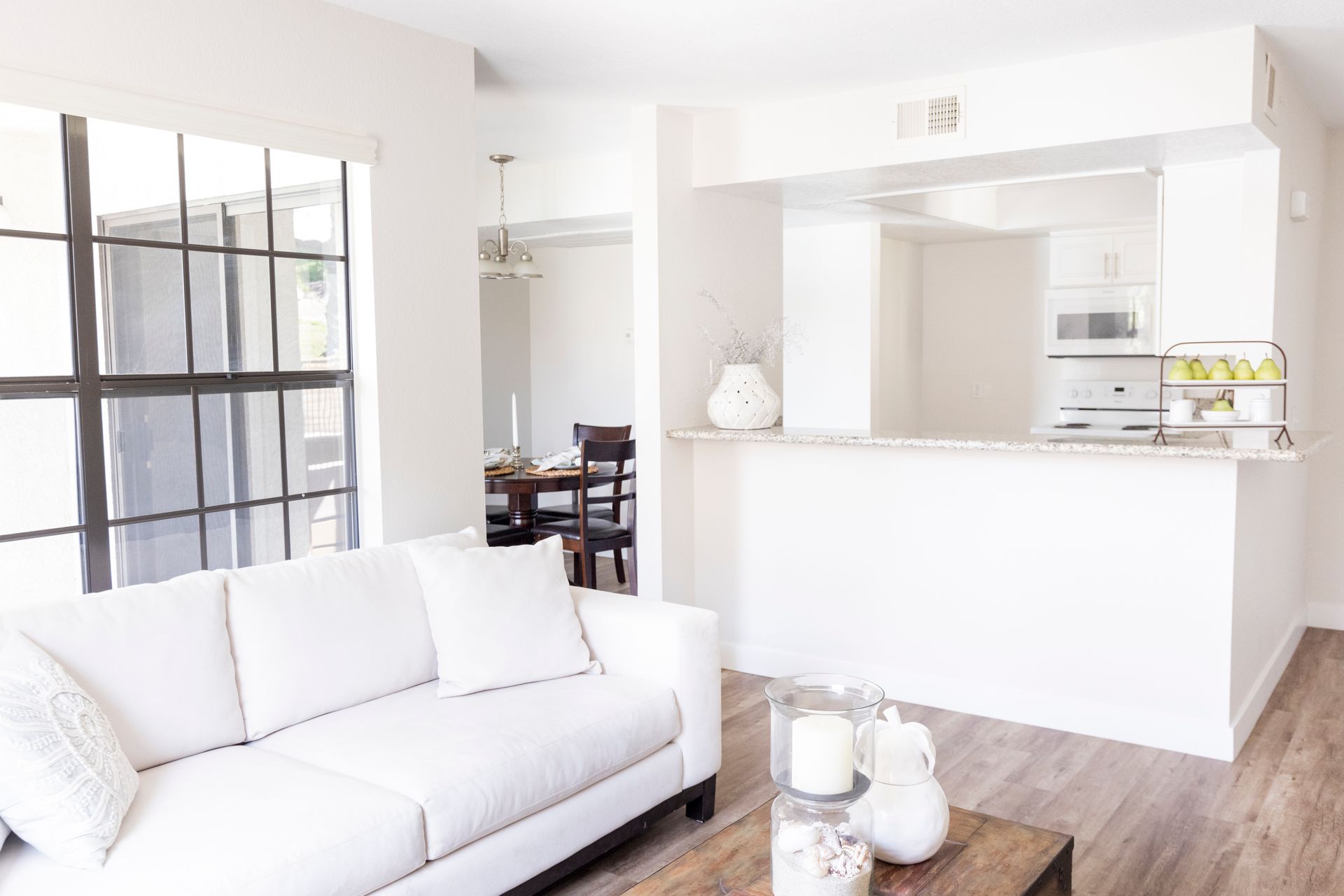 Living Room with a white couch and plenty of natural lighting alternate angle showing dining area in background