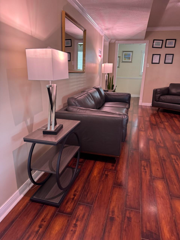Living room with leather sofa, end table with lamp, hardwood floors, and a mirror.