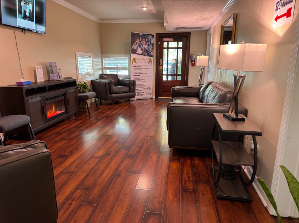 Waiting room with brown hardwood floor, dark leather furniture, and a fireplace.