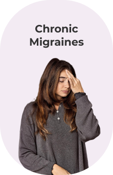 A woman with chronic migraines is holding her forehead