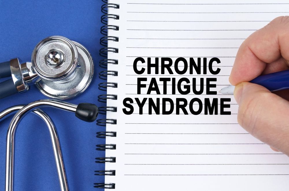 A person is writing in a notebook about chronic fatigue syndrome.