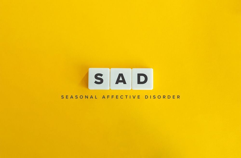 The word sad is written in scrabble tiles on a yellow background.