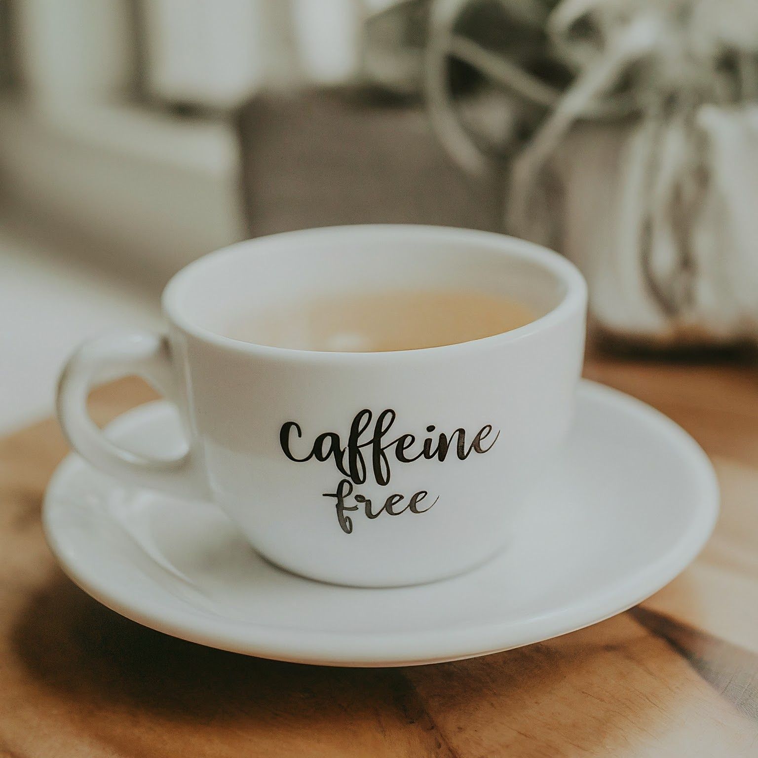 A cup of coffee on a saucer that says caffeine free