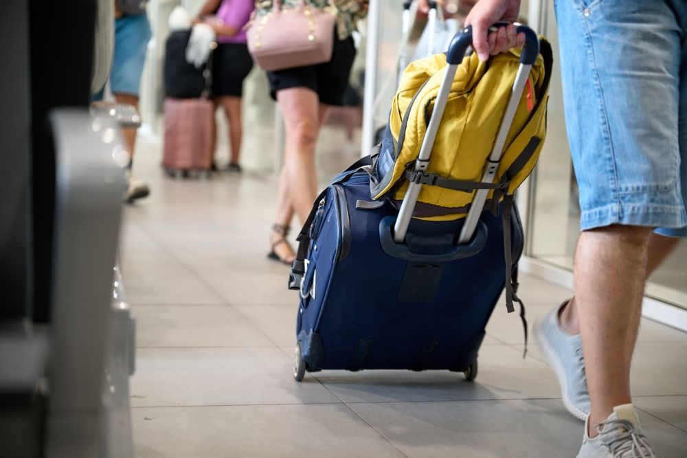 A man is pulling a suitcase with a backpack on it.