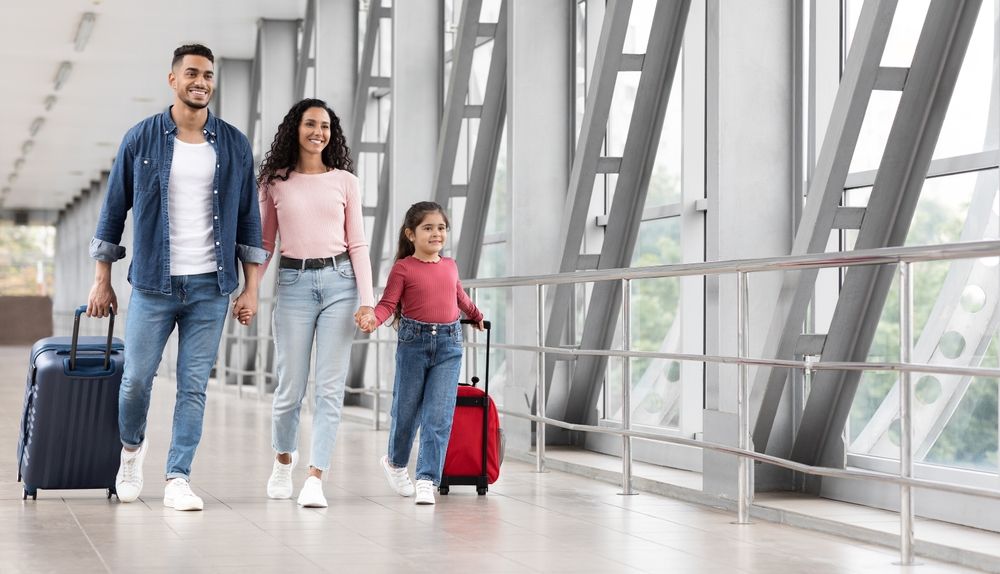 A family is walking through an airport with luggage.