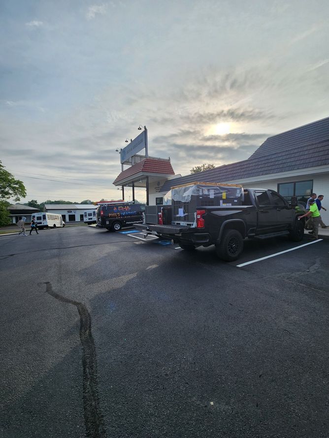 Black pickup truck parked outside a building with a sign, overcast sky.