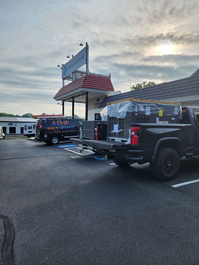 Black truck with equipment, black van with logo, parked in front of a building with a sign.