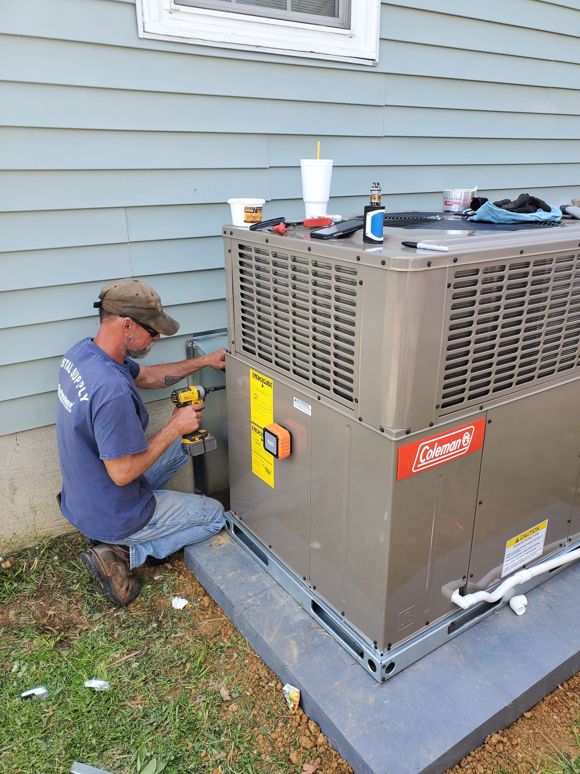 A man is working on an air conditioner outside of a house.