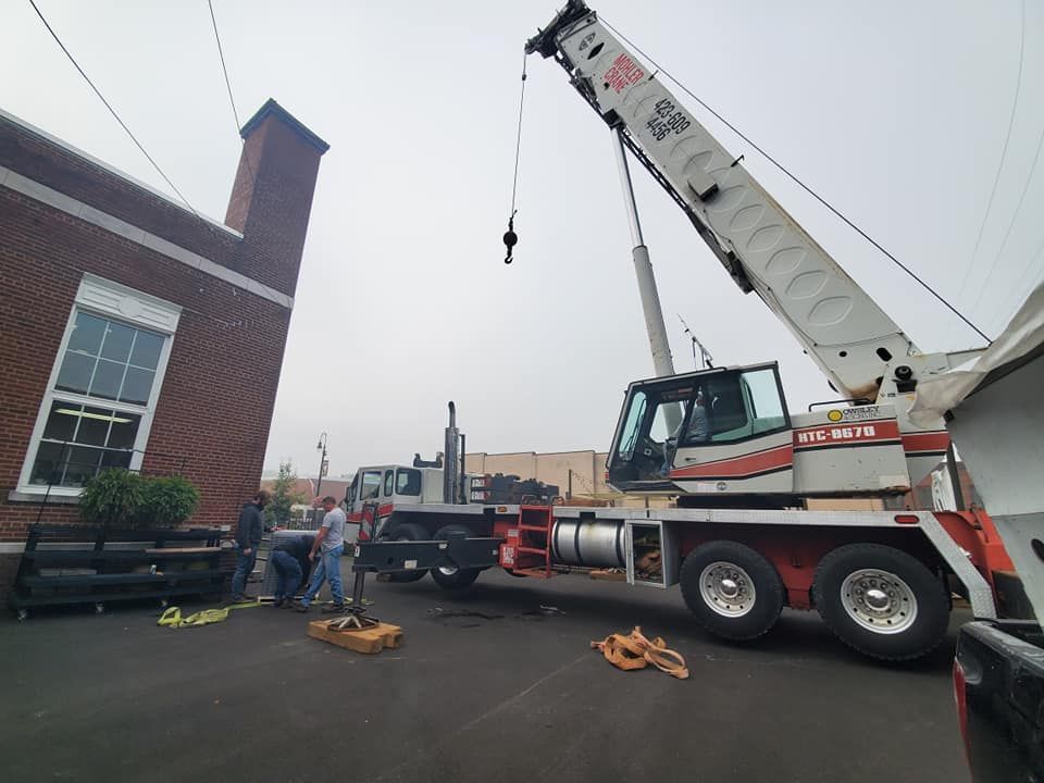 A crane is lifting a truck in front of a brick building.