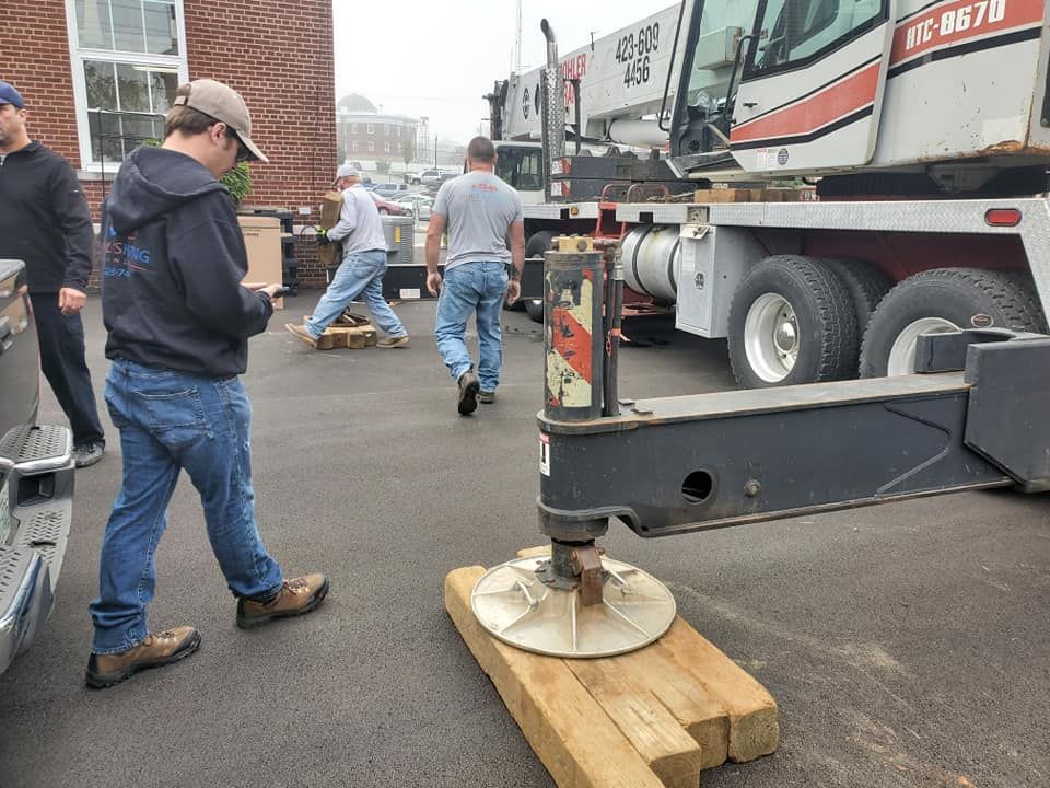 A group of men are working on a crane in a parking lot.