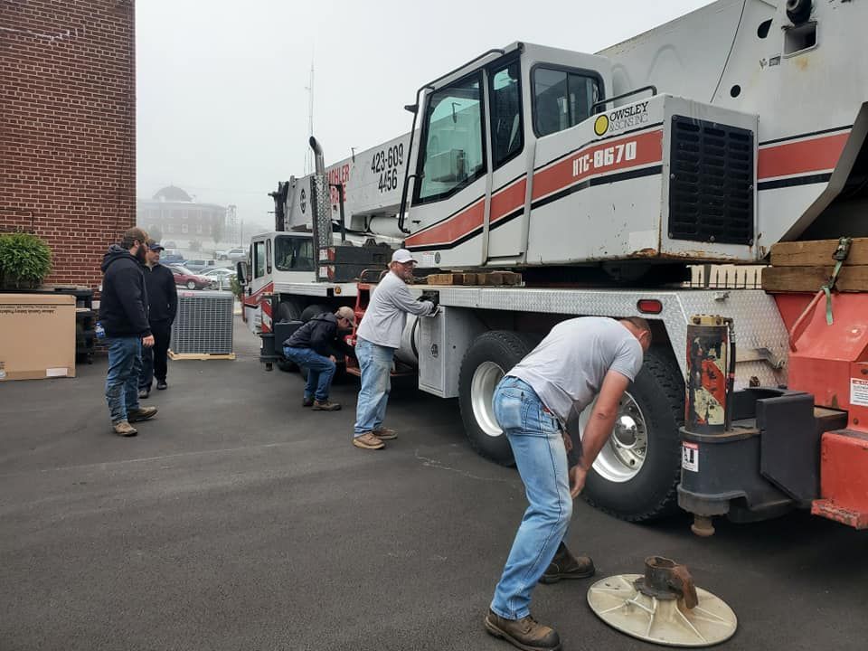 A group of men are working on a crane in a parking lot.