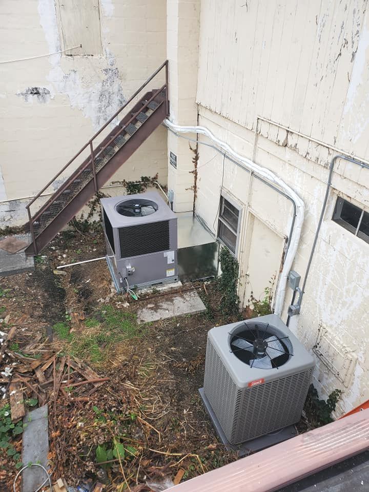 Two air conditioners are sitting on the side of a building.