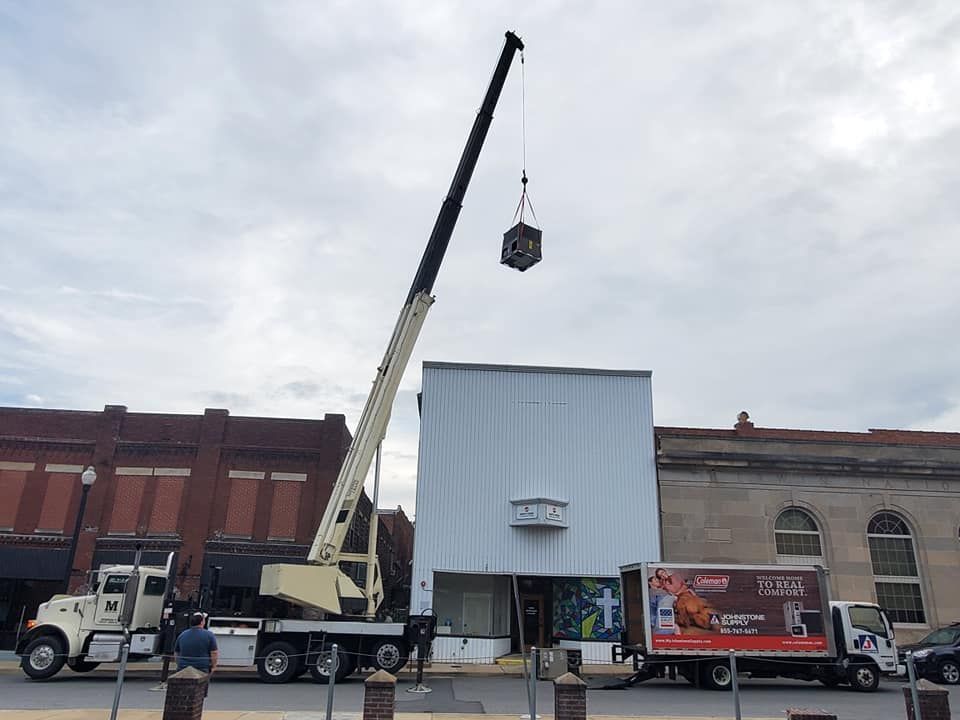 A large crane is lifting a box in front of a building