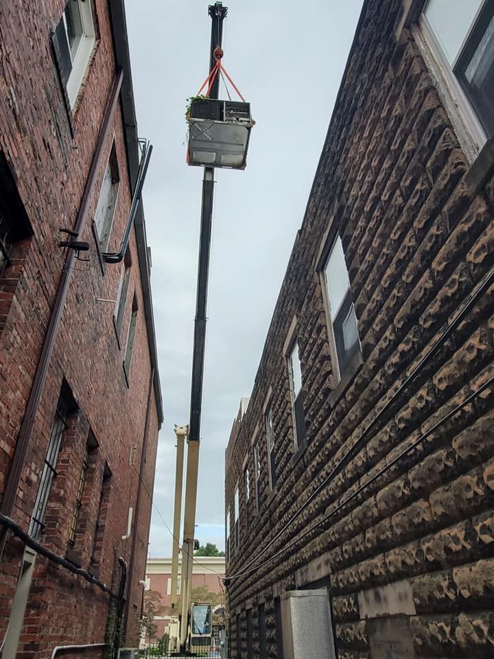 A crane is lifting a box between two brick buildings.