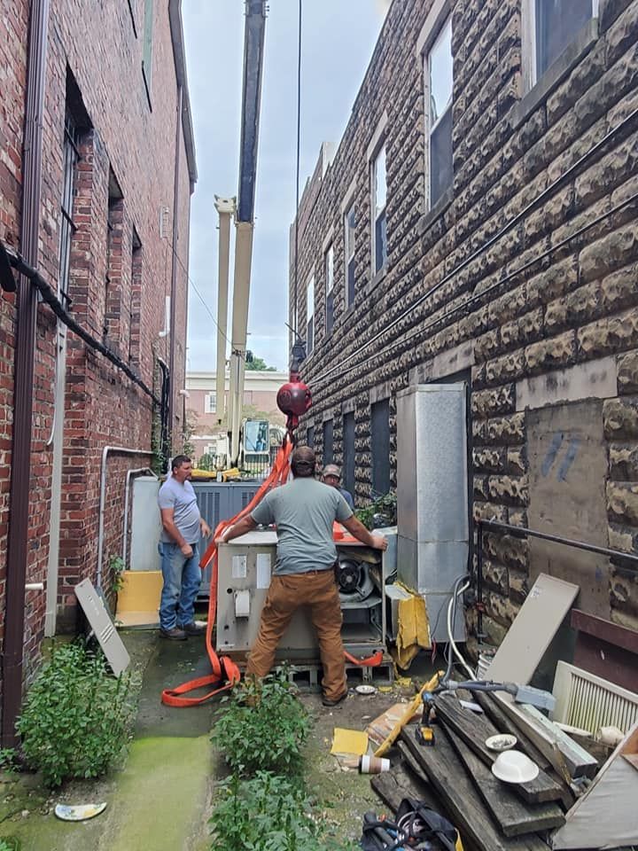 A man is standing next to a crane in a narrow alleyway between two buildings.