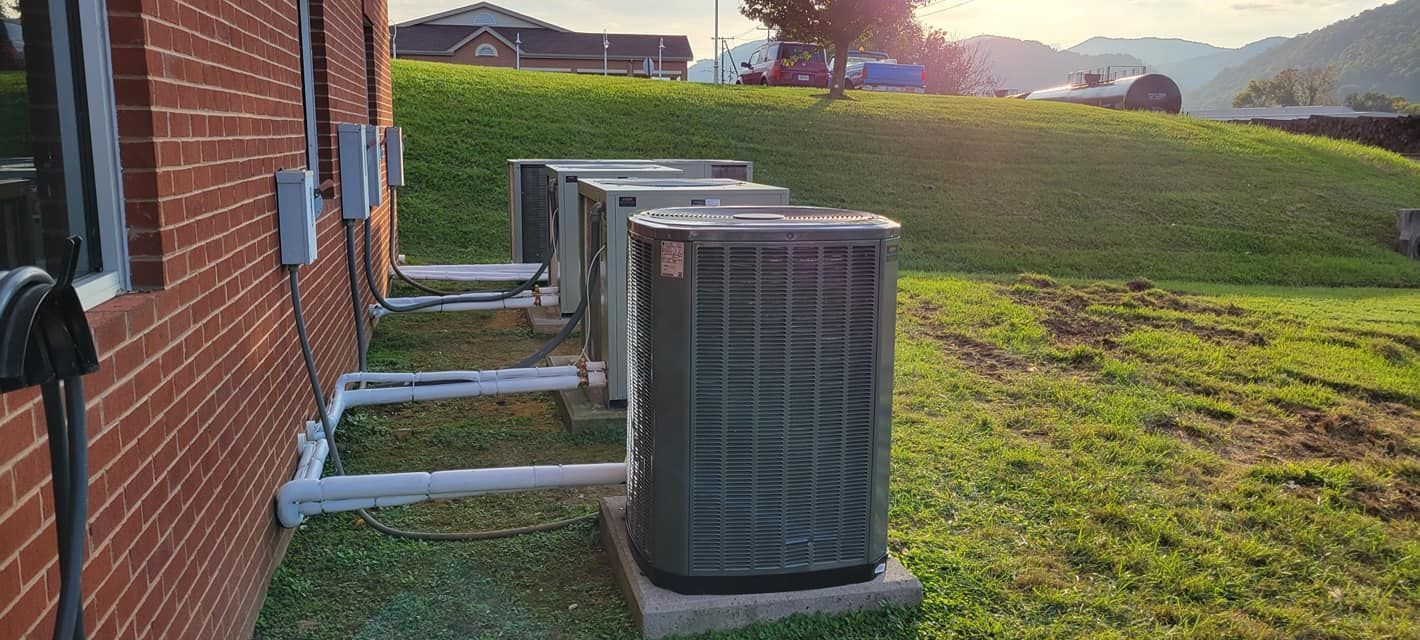A row of air conditioners are sitting outside of a brick building.
