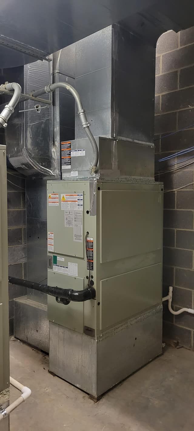 An air conditioner is sitting in a basement next to a brick wall.