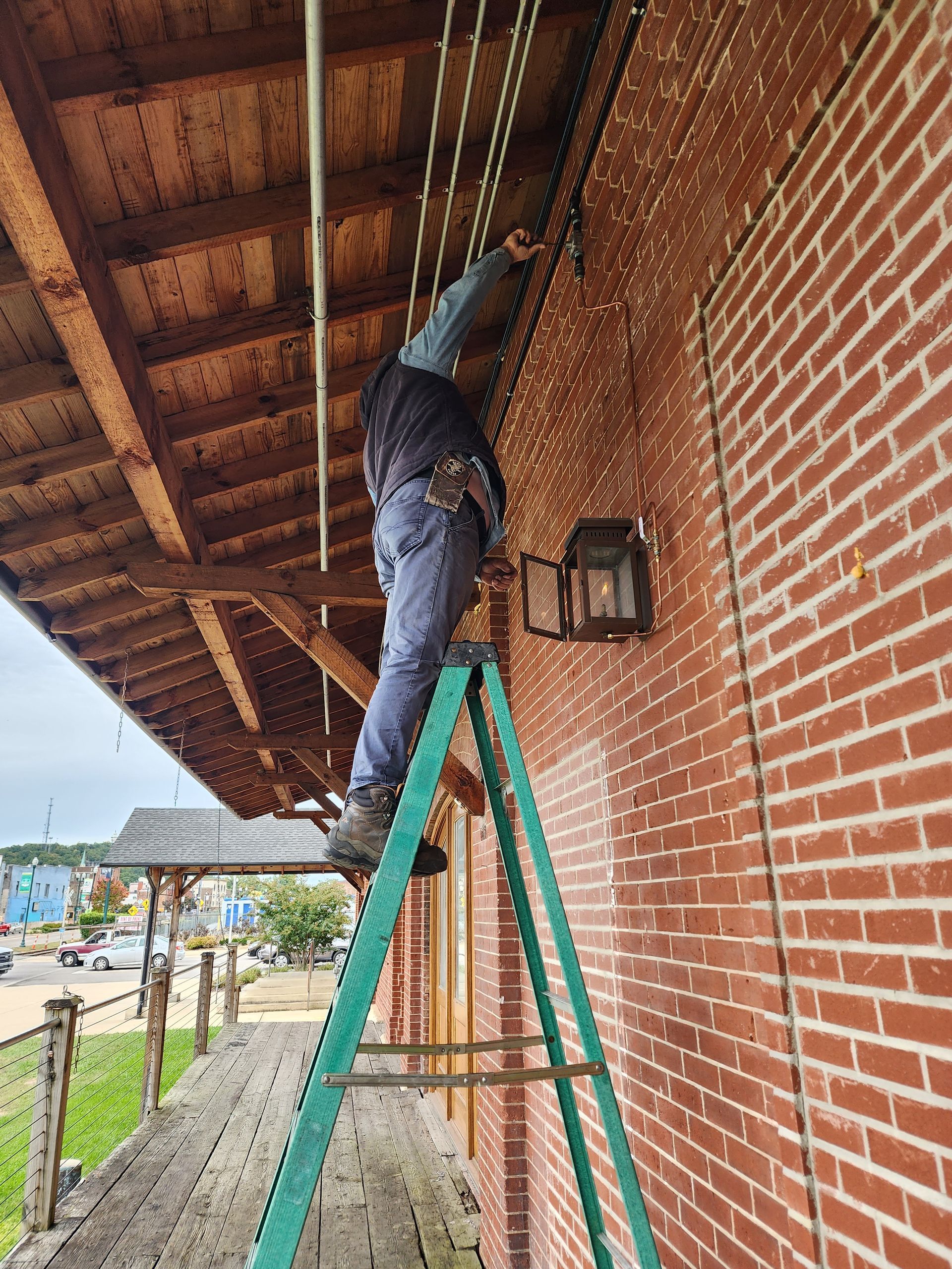 A man is standing on a ladder working on a brick building.
