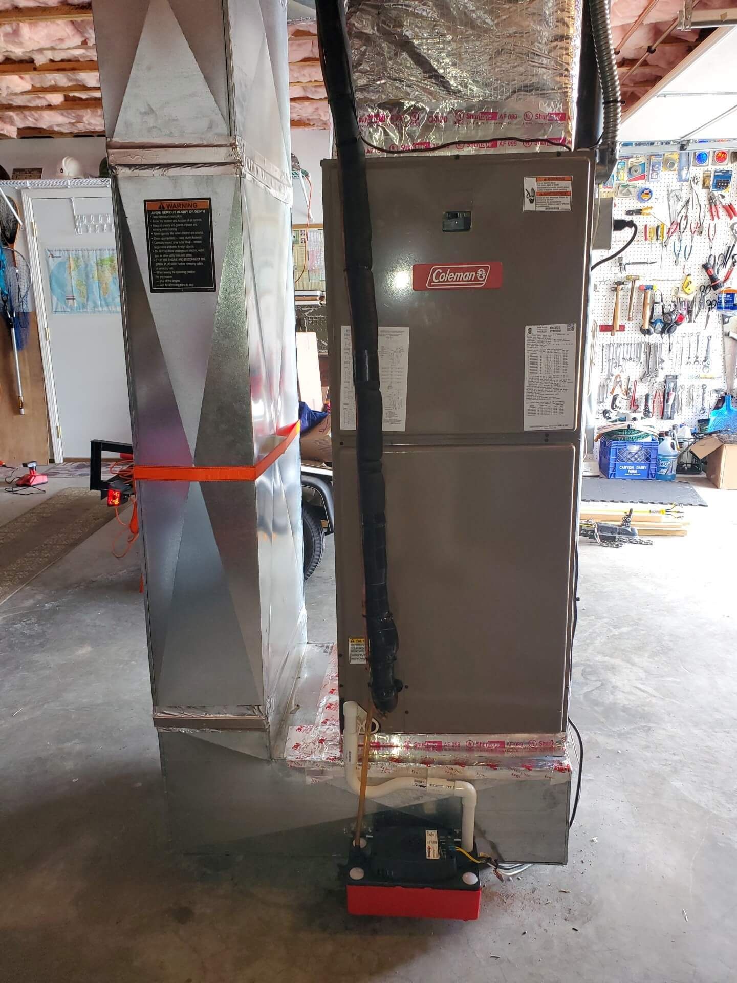 A large air conditioner is sitting in a garage next to a wall.