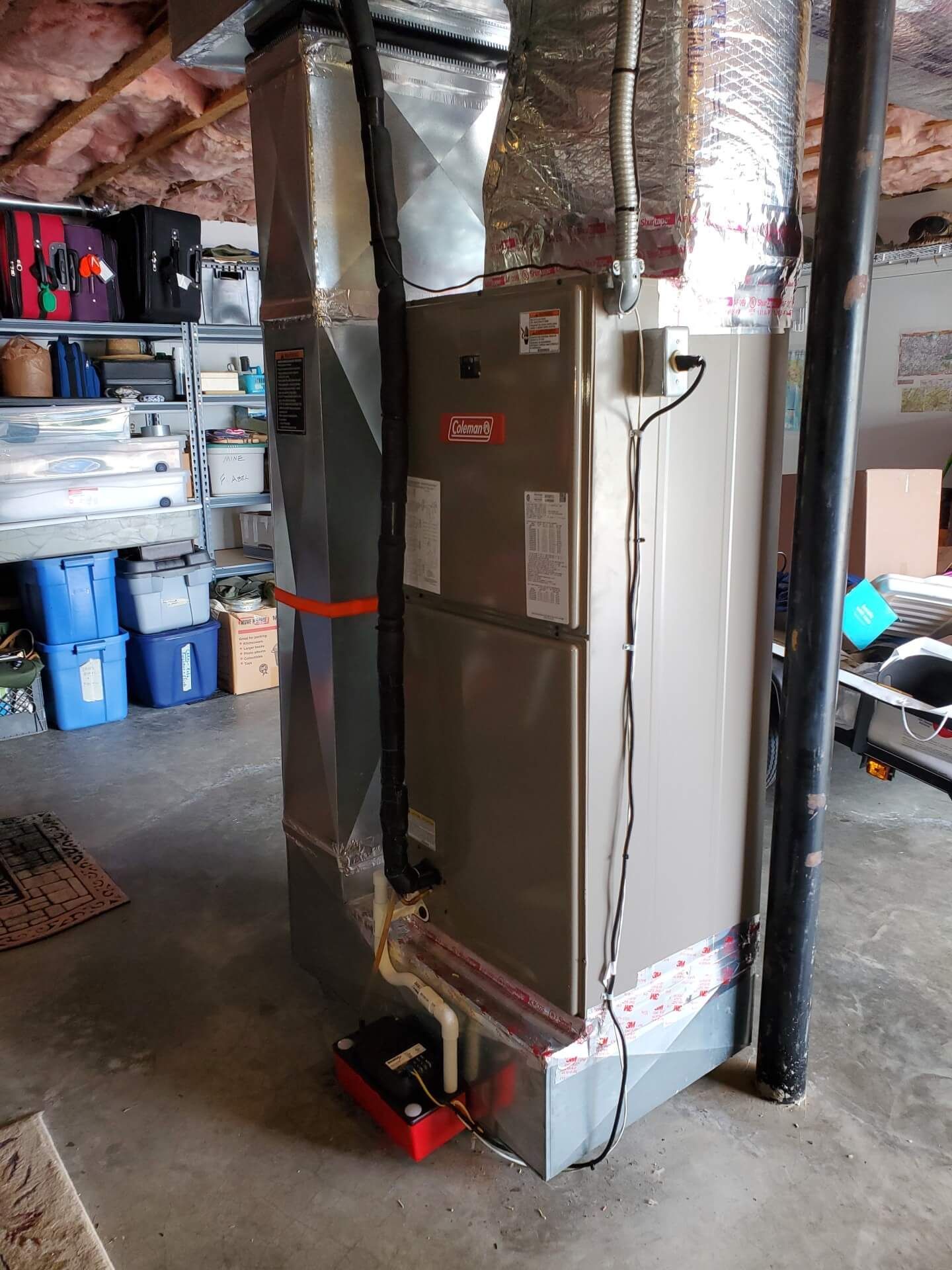 An air conditioner is sitting in a basement next to a pipe.