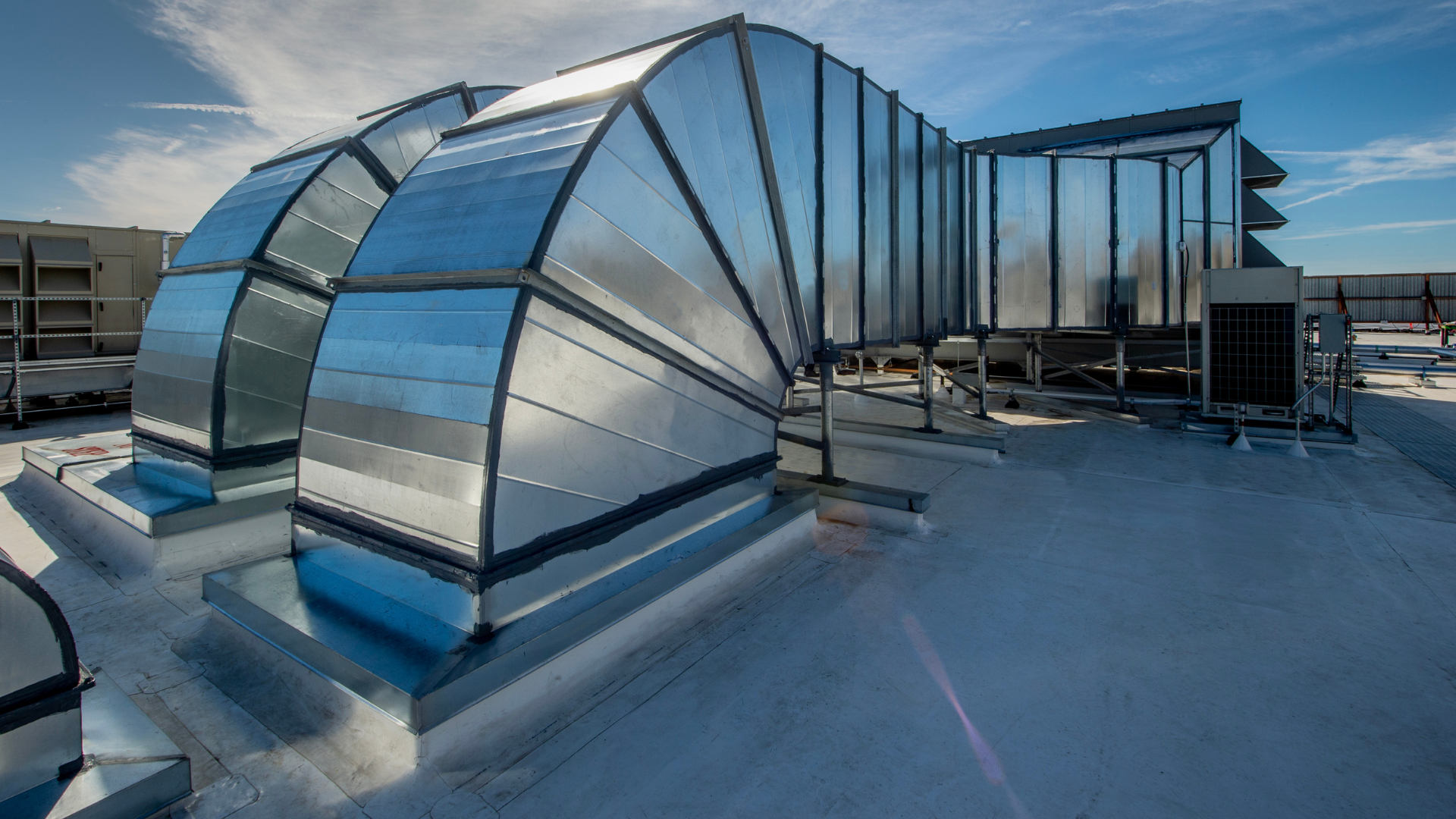 A large metal pipe is sitting on top of a snow covered roof.