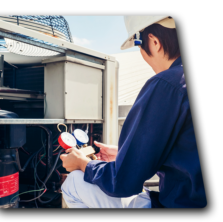 A man wearing a hard hat is working on an air conditioner