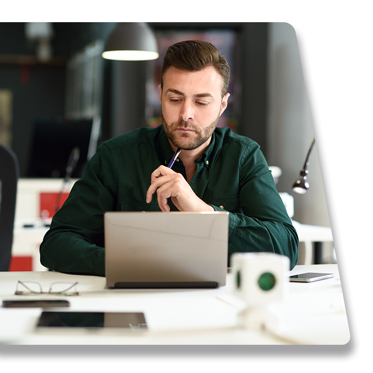 A man is sitting at a desk using a laptop computer.