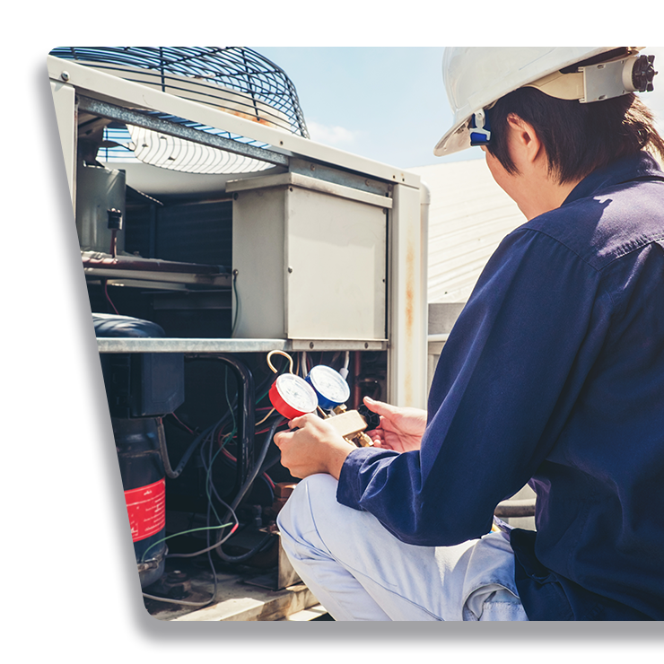 A man wearing a hard hat is working on an air conditioner.