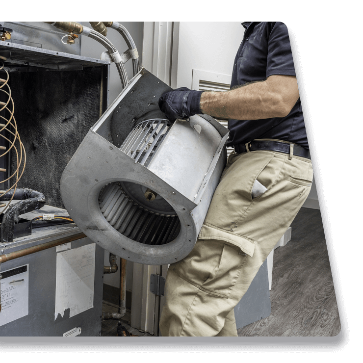 A man is holding a fan in his hands while working on an air conditioner.