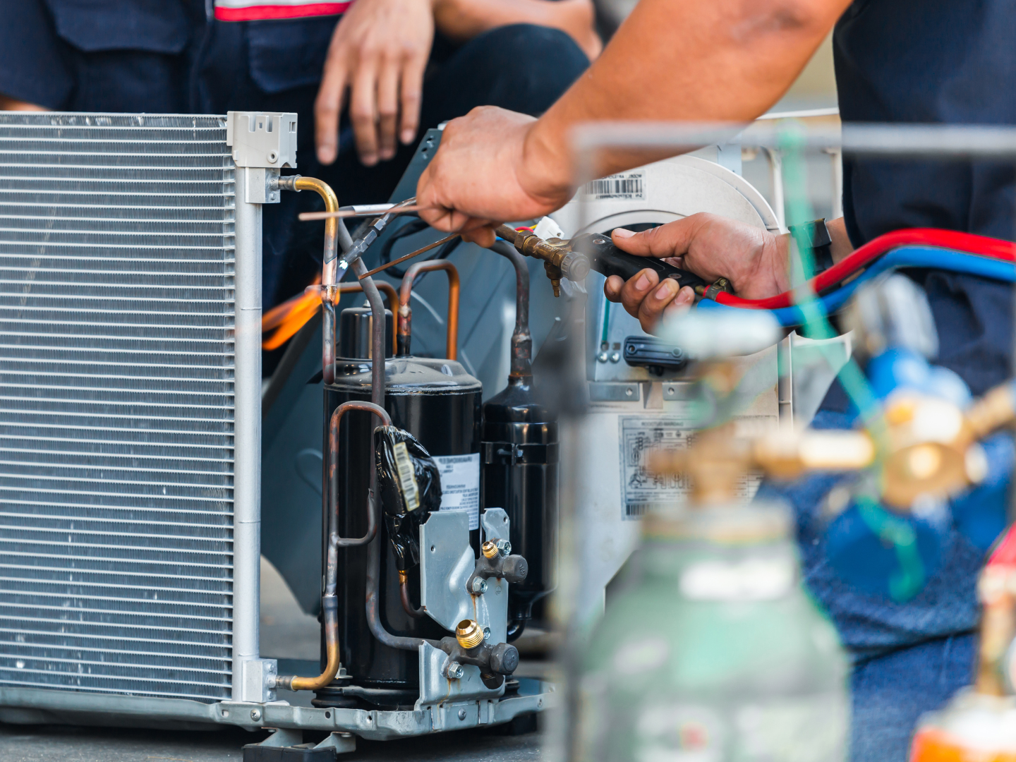 A man is working on a refrigerator with a welding torch.