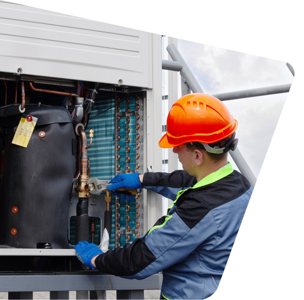 A man wearing a hard hat is working on a machine.