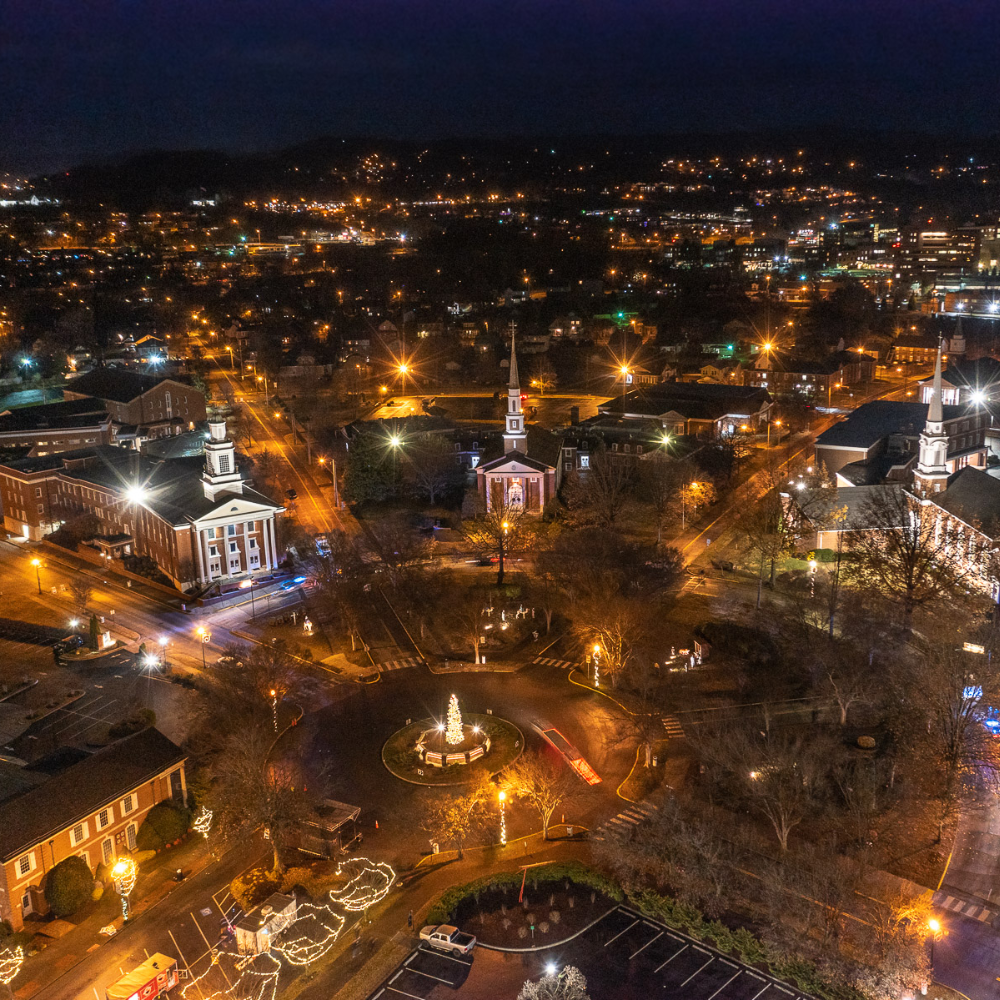 An aerial view of a city at night with a church in the middle