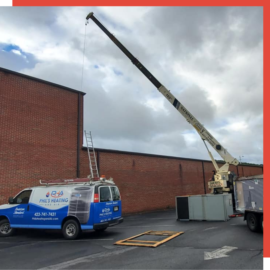 A van with a crane on top of it is parked in front of a brick building.