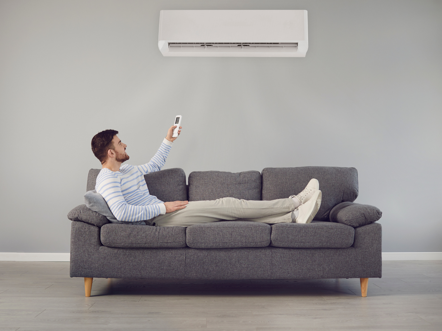 A man is laying on a couch holding a remote control.