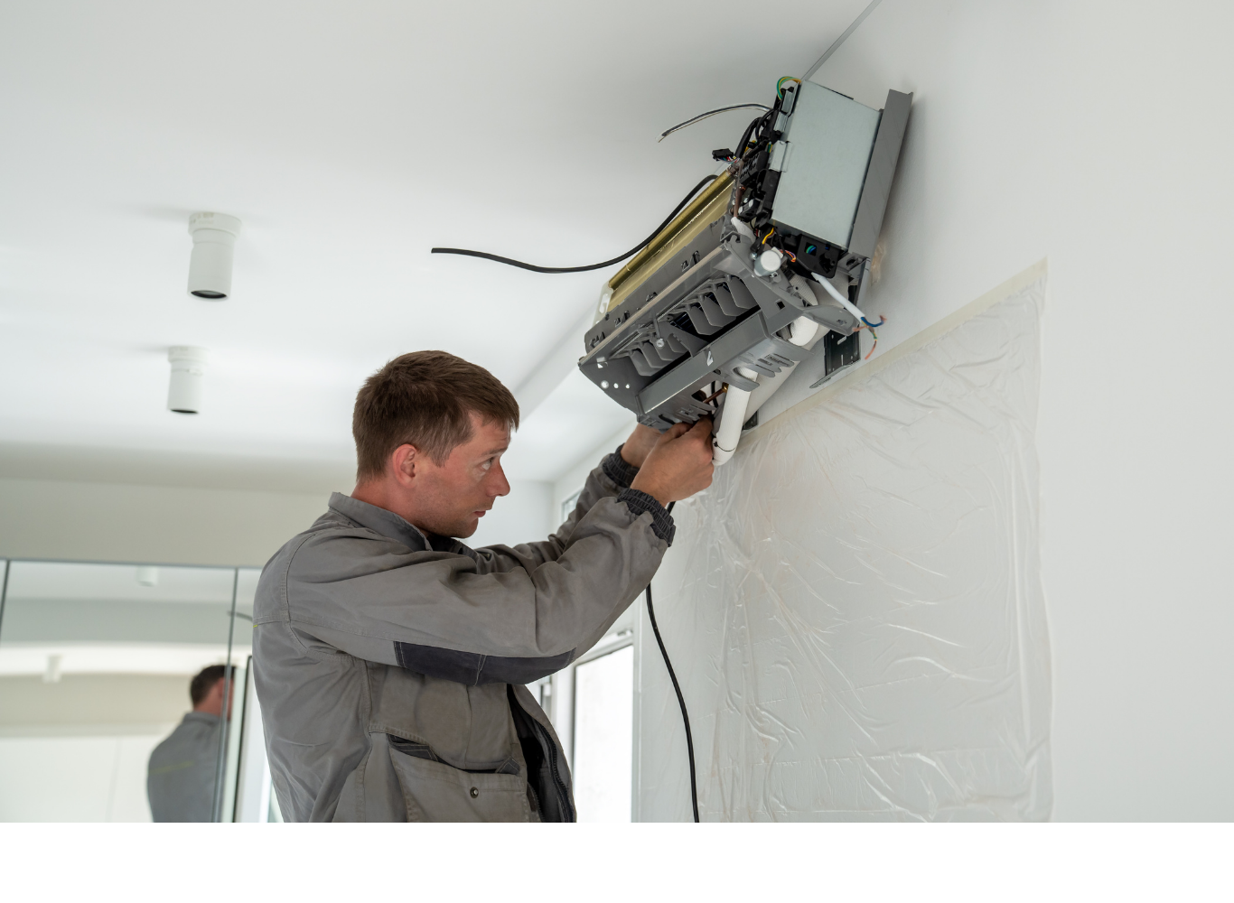 A man is installing an air conditioner on a wall.