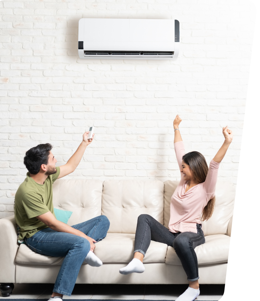 A man and a woman are sitting on a couch in front of an air conditioner.