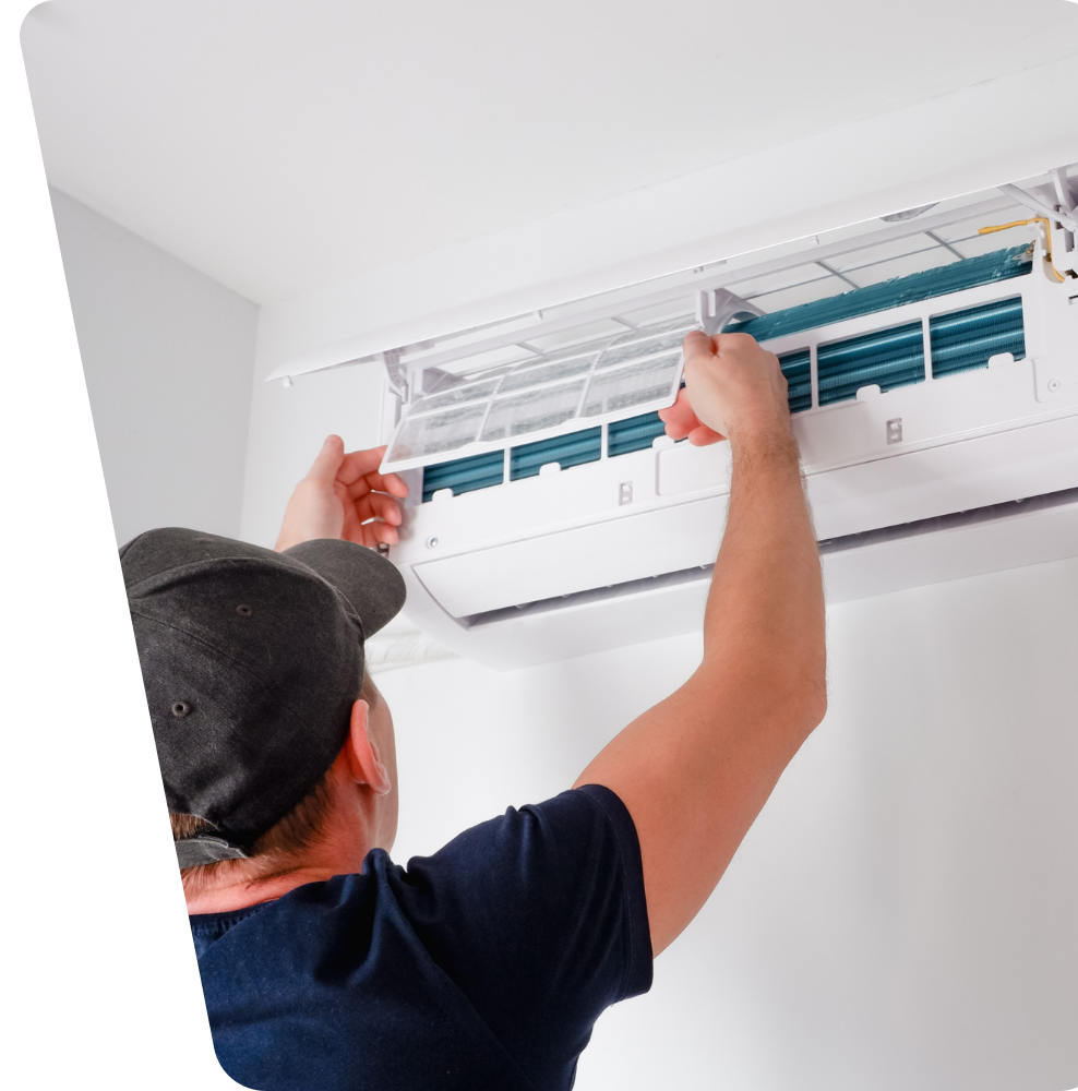 A man wearing a hat is working on an air conditioner.