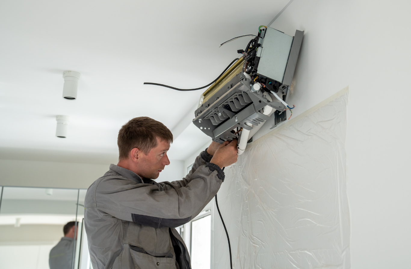 A man is installing an air conditioner on the wall.